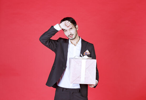 礼物一个穿着黑色西装的男人手里拿着一个紫色的礼盒 看上去又累又困人礼盒生日