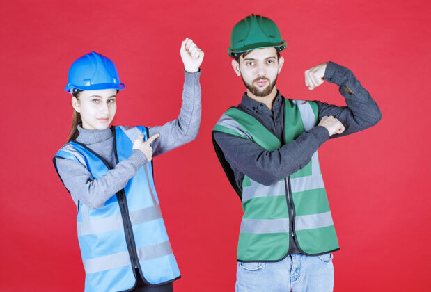 幸运戴着头盔的男女工程师感觉到了力量和积极姿势工人员工