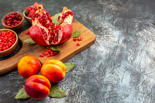 多汁前视图切碎的石榴和桃子放在深色的桌子上 花园里的果树果实前营养胡椒