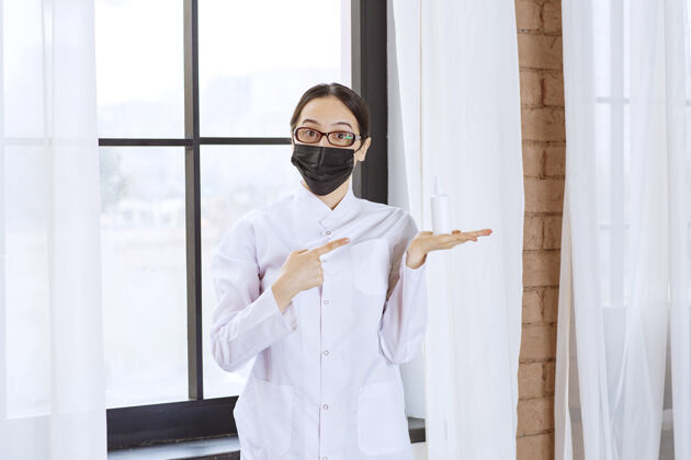 模特戴着黑面具和眼镜的医生站在窗边指着她的手姿势疾病感染