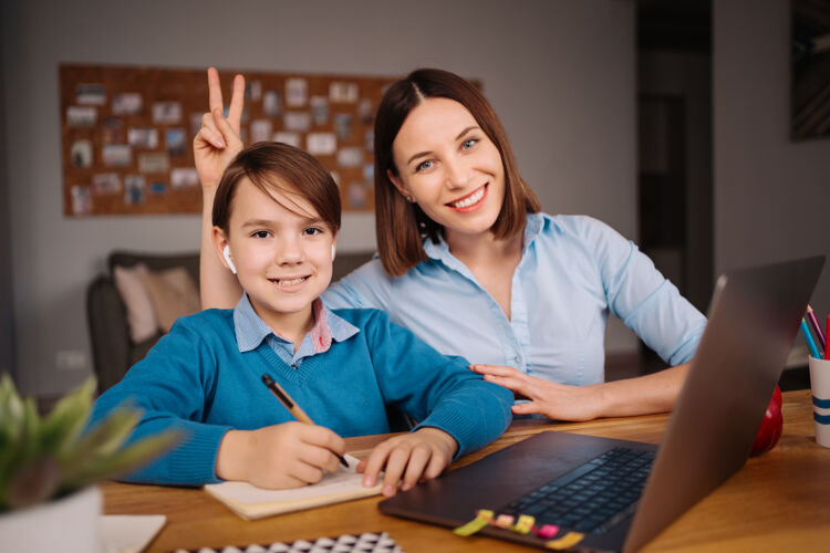 微笑一个未成年男孩用笔记本电脑和他妈妈旁边的老师打视频电话学习在线视频通话