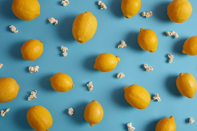 充满活力酸熟的黄色柠檬和甜甜的爆米花美丽的柑橘类水果组成的蓝色背景美味健康的热带水果含有大量维生素营养概念特写爆米花景观热带