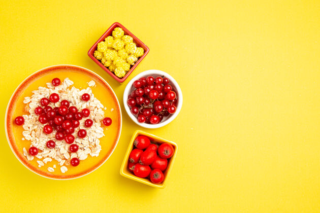 食物顶部特写查看浆果不同浆果黄色糖果燕麦片放在黄色的桌子上燕麦片糖果多汁