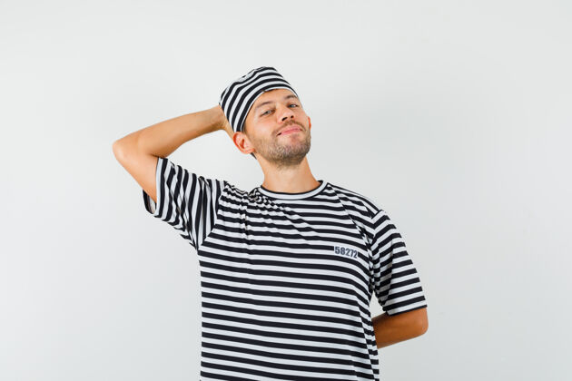 自信一个戴着条纹t恤帽子的年轻人把手放在脑后 看上去很放松男胡须手