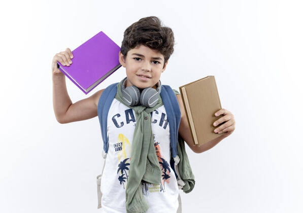 抱着高兴的小男生背着书包 戴着耳机 手里拿着书 背景是白色的请戴上耳机包