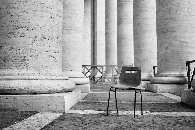 灰阶罗马一座有柱子的建筑中一把废弃塑料椅的灰阶照片圆柱生锈街道