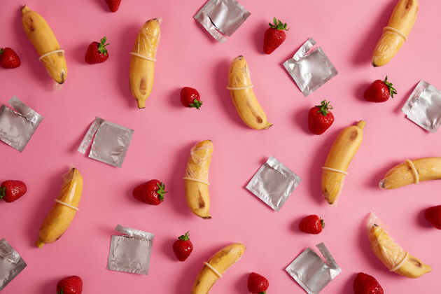 草莓超级安全的香蕉和草莓口味的避孕套 玫瑰色工作室背景 气味宜人天然橡胶乳胶制成的避孕药 高品质的材料自然的感觉和安全避孕灵活教育