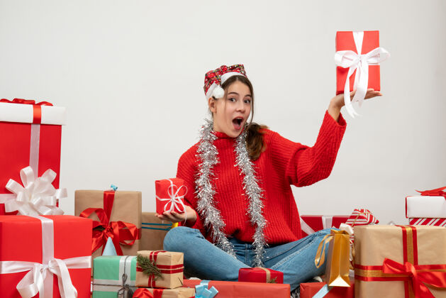 快乐前视图兴高采烈的女孩戴着圣诞帽拿着礼物围坐在礼物旁边礼物圣诞老人冬天