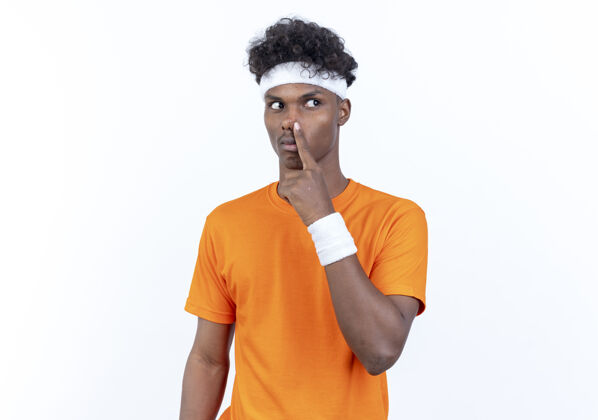 鼻子看着身边年轻的美国黑人运动男子戴着头带和腕带把手指放在鼻子上孤立的白色背景头带腕带年轻