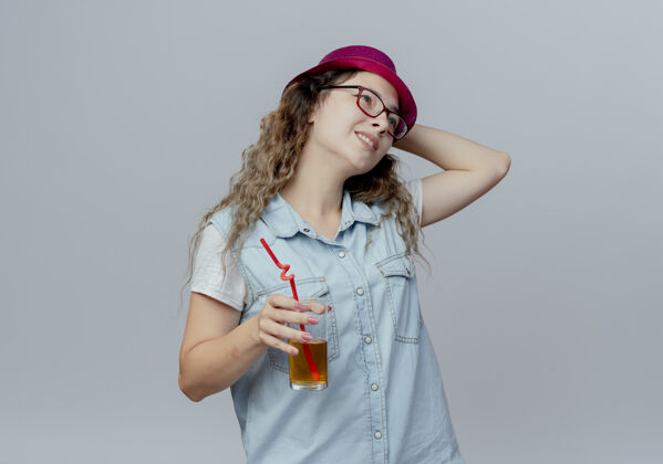 困惑的看着身边迷茫的小女孩 戴着粉红色的帽子 手里拿着一杯果汁 手放在白色背景上孤立的帽子上壁板拿着杯子