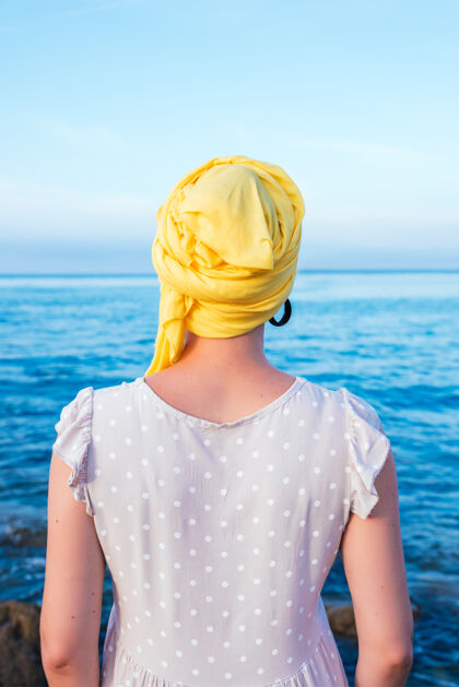 海景一个戴着黄围巾的女人 她无毛的头在凝视着海的地平线决定自由水