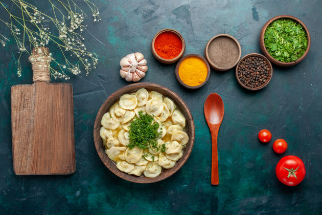 不同俯瞰美味的饺子汤 用青菜和不同的调味料在深色的面团上做汤面蔬菜食品景观勺子木勺