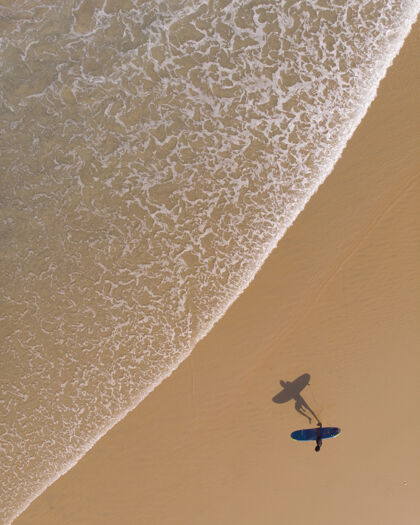 度假村顶视图拍摄一个人与冲浪板走在瓦尔卡拉海滩人海滩海洋