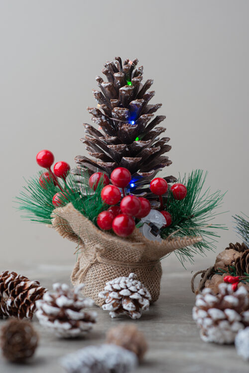 圣诞节用冬青浆果和树枝装饰的松果放在大理石桌上圆锥体冬天假日