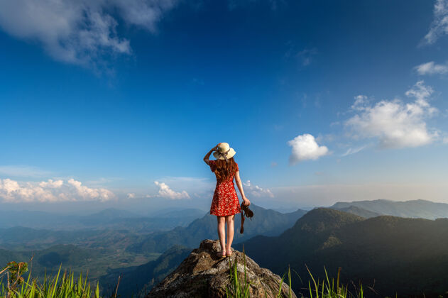 成功女人手持相机 站在岩石上的自然旅游概念享受立场悬崖