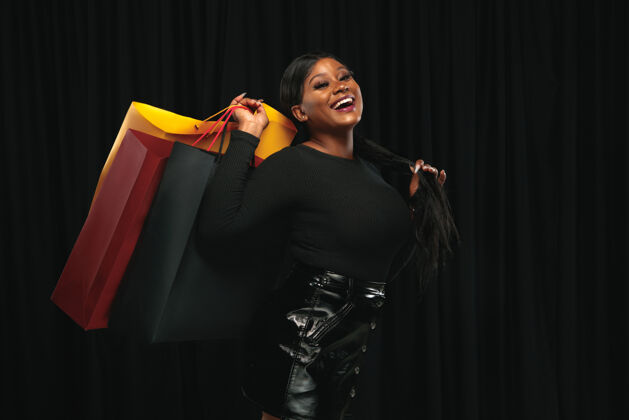 Young年轻的非洲裔美国妇女购物与五颜六色的黑色包装JoySaleMagic