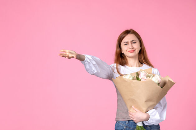 花束正面图：年轻女性 带花朵 作为女性节礼物 粉色背景 水平女性三月 女性平等 玫瑰 爱情 性感年轻的女性花人