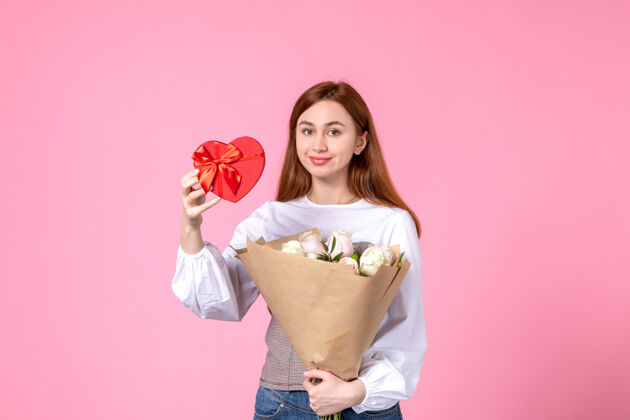 年轻女性正面图：年轻女性 带鲜花 在粉色背景上作为妇女节礼物 水平三月女性平等性感女性约会玫瑰人礼物玫瑰