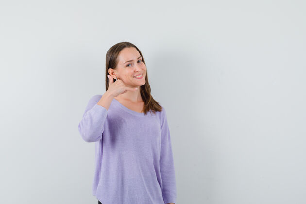 女性身着淡紫色上衣的年轻女性 展示着打电话的姿势 看上去很高兴皮肤健康干净