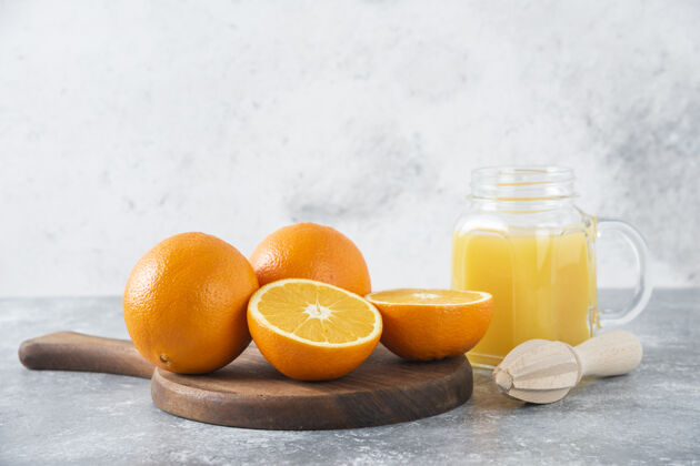 热带石桌上放着一杯果汁和新鲜的橙子异国情调橙子天然