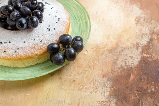 蓝莓侧面特写镜头蛋糕一个开胃的蛋糕与葡萄串糖粉在盘子上食品糖粉末