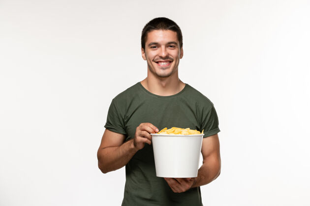 杯子正面图身穿绿色t恤的年轻男性 带着土豆cips看电影 在白墙上微笑着看电影人男性孤独电影电影院电影视图微笑
