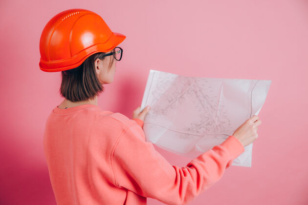 白色在粉色背景下微笑的女工建筑工人建筑头盔头盔明亮成人