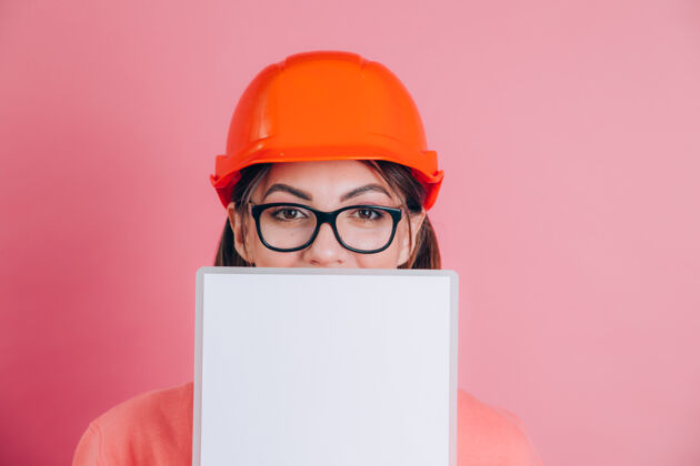 建筑面带微笑的女建筑工人手持白色的空白标志牌 背景是粉色的建筑头盔工作工程师承包商