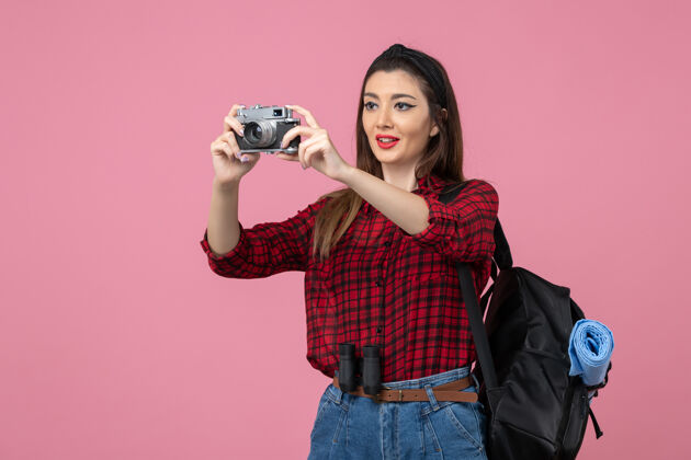 漂亮前视图年轻女性用相机在粉色背景上拍照女性照片颜色年轻女性照片微笑