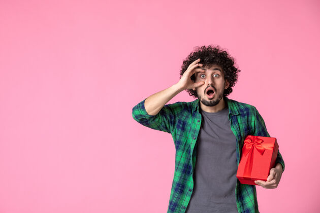 人浅粉色墙上红色包裹的年轻男性正面图卷发日期礼物