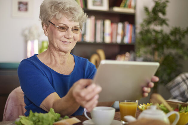 当代开朗的奶奶使用het数码平板电脑享受移动成人