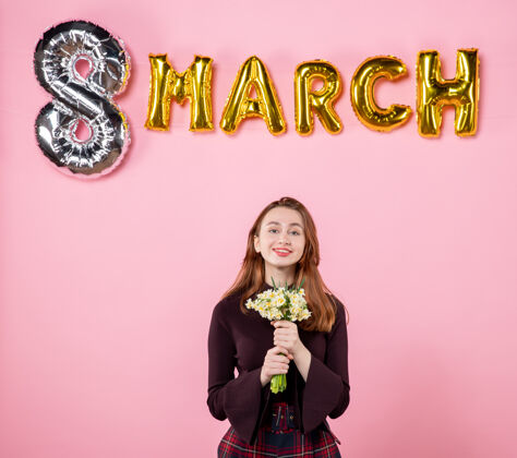 8正面图：手拿鲜花的年轻女性 粉色背景上的三月装饰 呈现妇女节三月结婚激情平等感性妇女节8三月