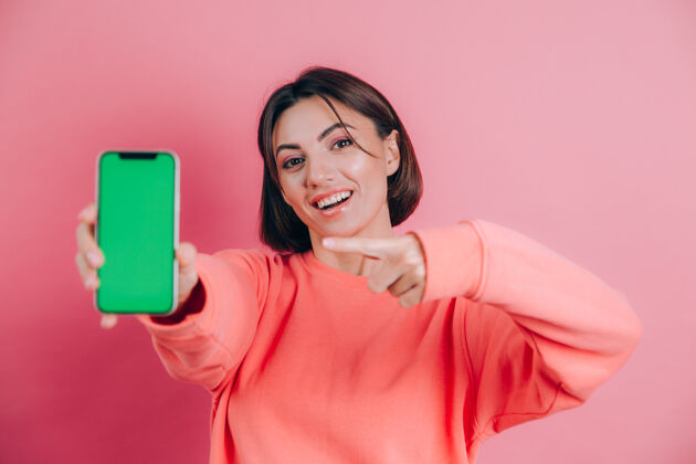 电话看这部手机开心快乐的女人用食指指着空白屏幕 显示出现代装置 开心惊喜的情绪手机欢呼肖像