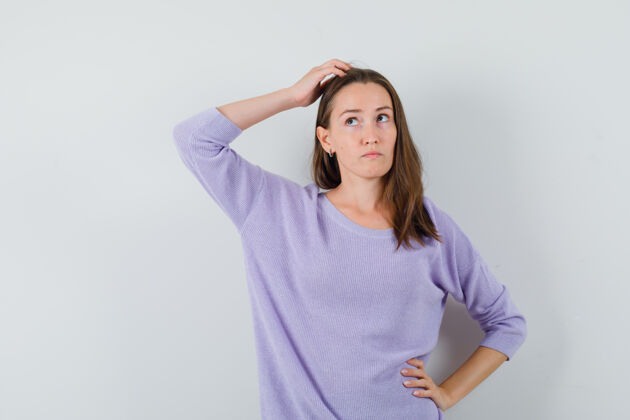 自信年轻的女性手举在头上 一边看着淡紫色的衬衫 看着沉思衬衫优雅而