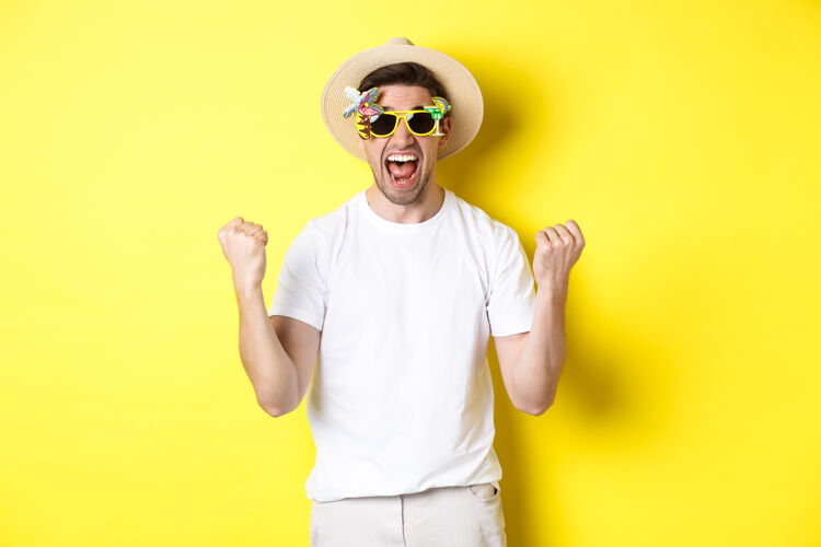 男人快乐的家伙去度假 获胜或庆祝 戴着夏帽和太阳镜游客看起来很兴奋 站在黄色的背景下帽子黄色工作室