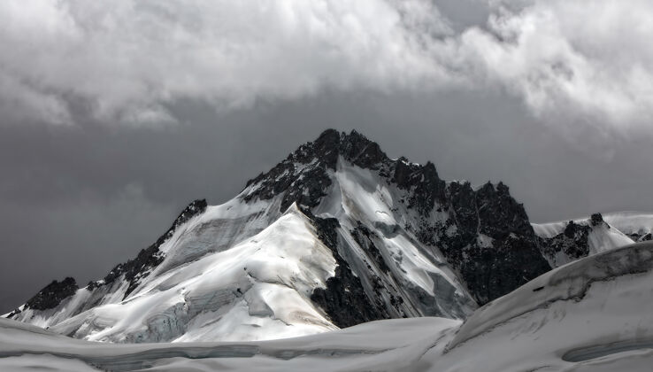冰白天多云的天空下白雪覆盖着高山山脉辉光山