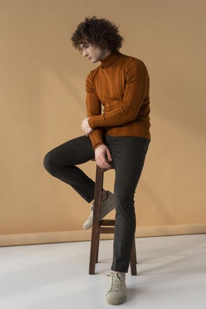 模特卷发男人穿着棕色上衣摆姿势时尚男性椅子