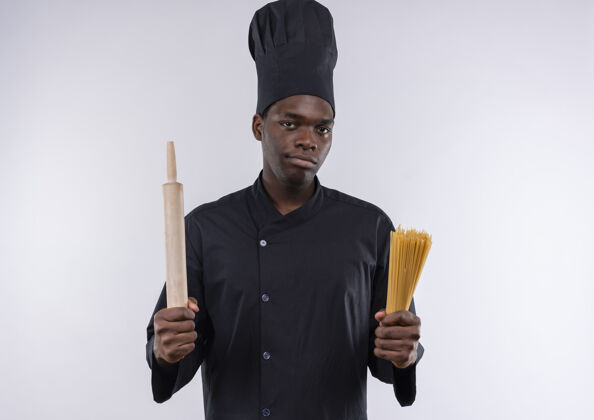 束年轻自信的美国黑人厨师穿着厨师制服 拿着擀面杖和一堆意大利面放在白色的地板上 留有复印空间卷厨师意大利面