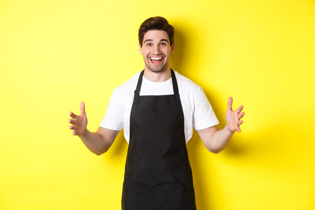 男人快乐的咖啡师拿着大东西 塑造大物体 站在黄色背景上厨师年轻黄色