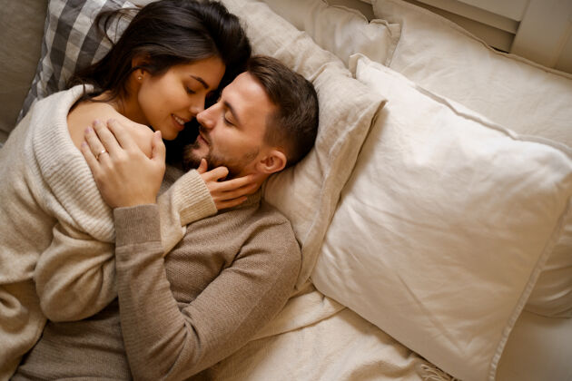 女人美丽的年轻幸福的夫妇在床上放松 微笑 拥抱帅哥关系放松