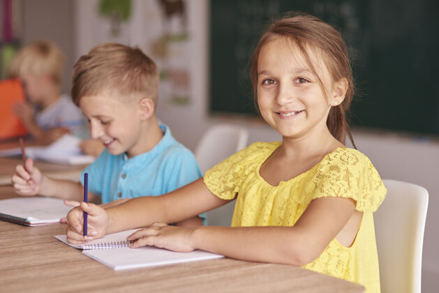 姿势男孩和女孩在一张桌子上写作学生智慧