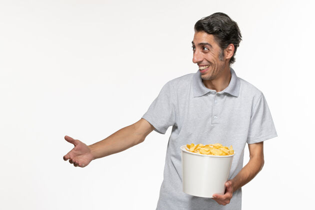 年轻的男性正面图年轻男性在白色的表面上笑着吃薯片电影院前面土豆