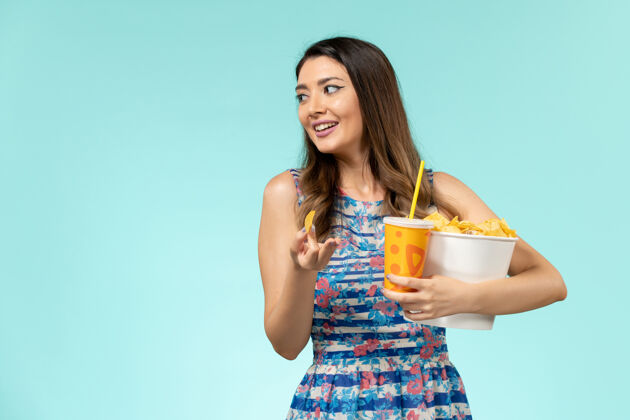 封面女郎正面图年轻的女性拿着篮子和薯片 在蓝色的水面上喝水年轻女性性感女性