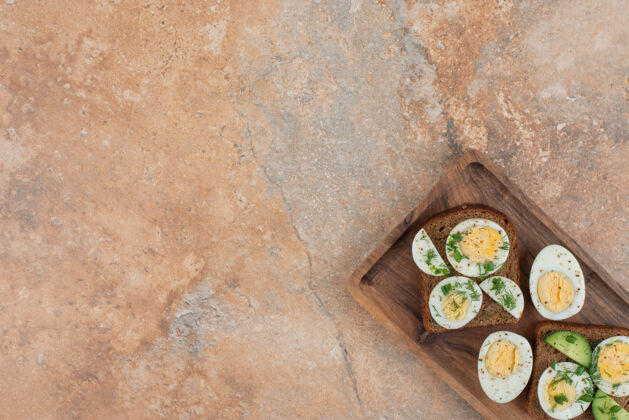 绿色两杯烤黄瓜和煮鸡蛋放在大理石桌上吐司美味板子