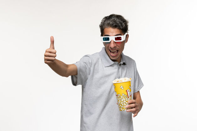 商人正面图：戴着d型太阳镜的年轻男性手持爆米花站在白色的地面上爆米花太阳镜孤独