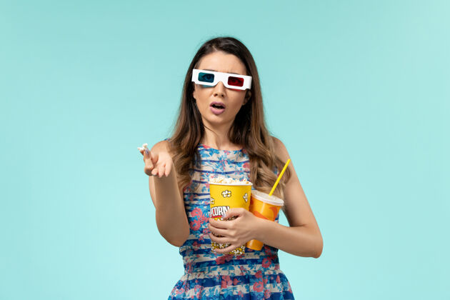 包装正面图年轻女性拿着爆米花包 戴着d墨镜在蓝色表面喝酒电影性感电影