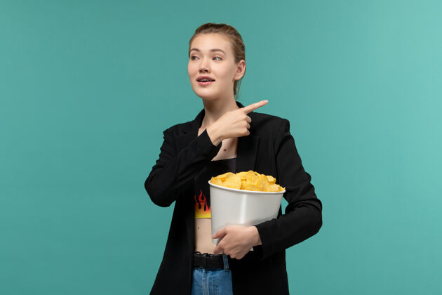 员工正面图：年轻女性在蓝色桌子上吃薯片看电影土豆年轻女性电影院