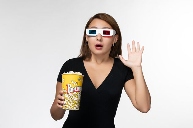 年轻女性正面图戴着d型太阳镜拿着爆米花的年轻女性在白色表面看电影抱太阳镜电影
