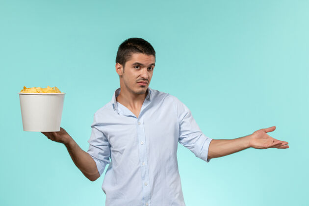 电影院正面图：年轻的男性拿着蓝面薯片的篮子孤独远程篮子