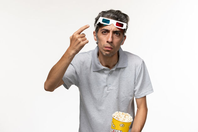 年轻的男正面图年轻男性手持爆米花包 戴着d墨镜 白色表面护目镜前面工人